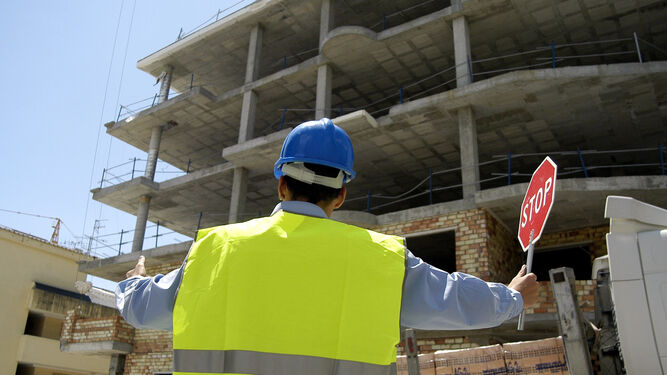 Un empleado de la construcción frente a un edificio de viviendas en Málaga.