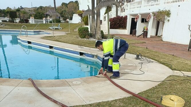 Un operario sustrayendo el agua de la piscina.