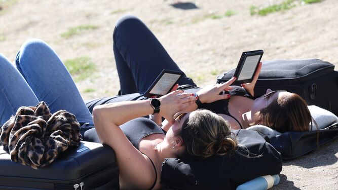 Turistas leen, rodeadas por sus maletas, en una playa de Málaga este mes de enero.
