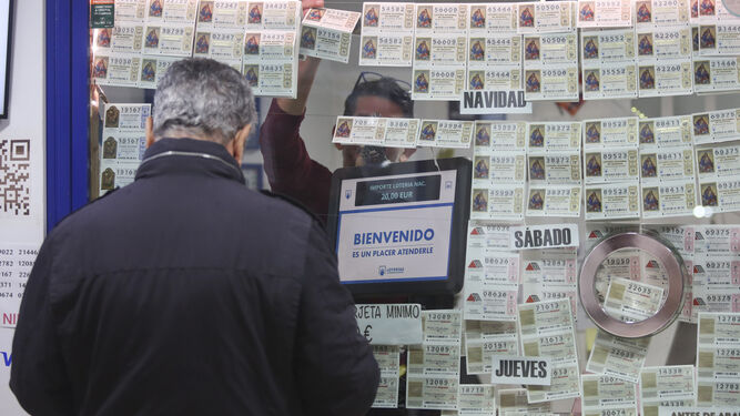 Un hombre compra lotería en una administración de Málaga.
