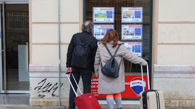 Turistas miran anuncios de casas en venta en Málaga.