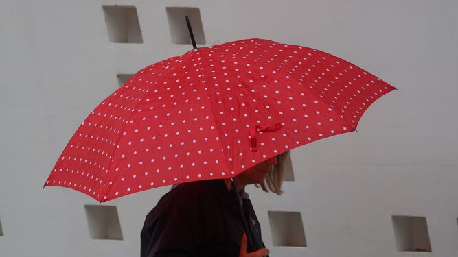 Una mujer se protege de la lluvia utilizando un paraguas.