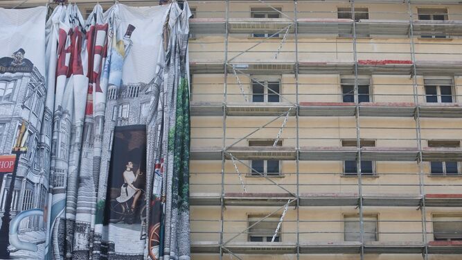 Retiran una lona de publicidad de unos andamios en el centro de Málaga.