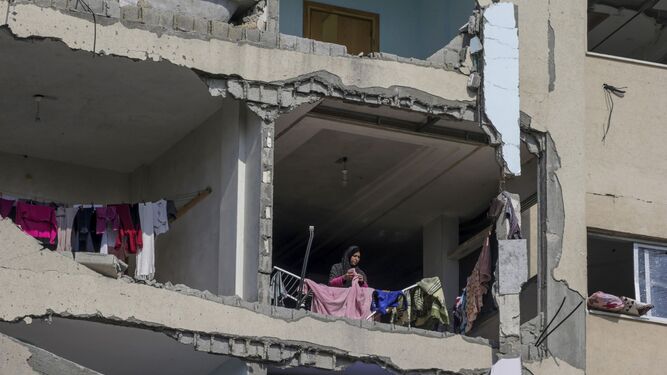 Una mujer tiende la ropa en un edificio destruido por bombardeos israelíes