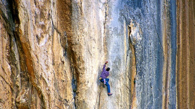 Una persona escala una de las paredes más verticales de El Chorro.