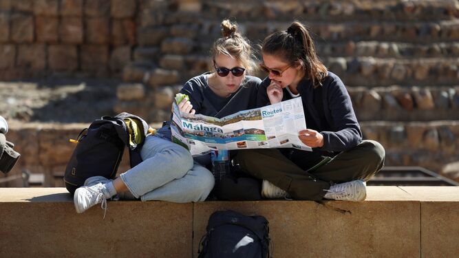 Dos turistas consultan un mapa sentadas en la calle Alcazabilla.