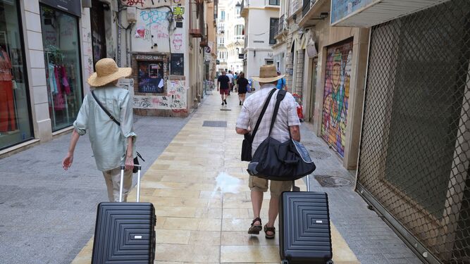 Dos turistas con sus maletas por el centro de Málaga.