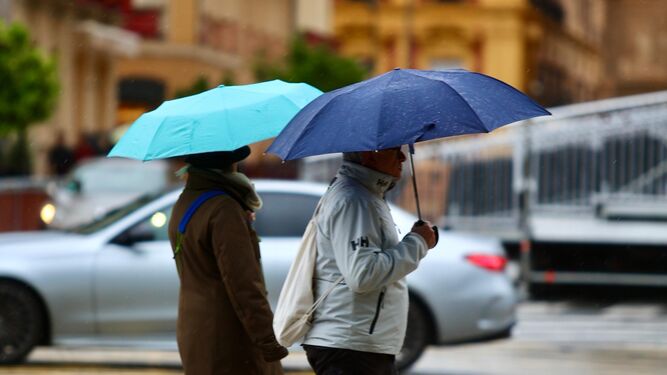 Dos personas se protegen de la lluvia en el centro, este sábado.