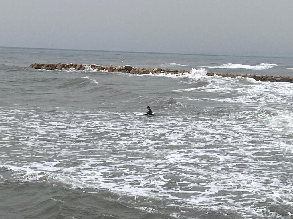 Un surfero en Torrox Costa, pese a la calima.