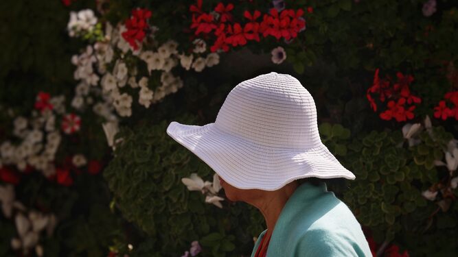 Una mujer con sombrero y rebeca pasea por Málaga